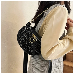 Detail of a black tweed crescent bag with gold zipper ring and chain shoulder strap