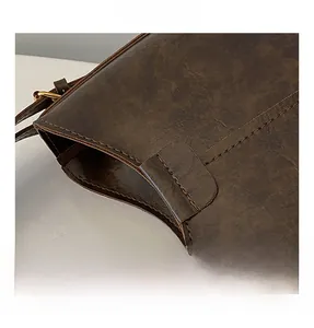 Close-up of vintage brown leather bag featuring precise stitching and gold metal hardware