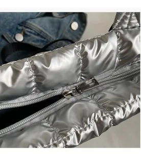 Detailed close-up of smooth silver metal zipper on quilted puffer shoulder bag