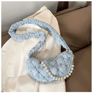 Detail of light blue quilted handbag featuring pearl handle and pleated shoulder strap
