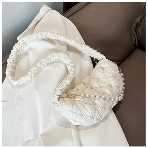Detail of cream pleated quilted shoulder bag featuring elegant pearl chain and soft texture