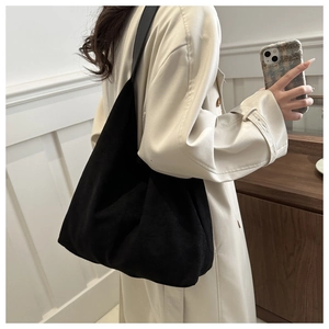 Detailed side view of a large black matte tote bag with wide strap worn on shoulder