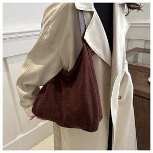 Close-up of matte dark brown suede hobo bag styled with a beige trench coat for autumn