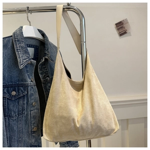 Detailed view of beige suede tote bag with wide shoulder strap on a metal hanger