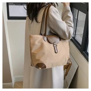 Detail of the high-capacity khaki tote bag with premium brown leather strap accents
