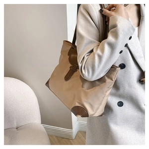 Detail view of large khaki tote bag with brown leather accents on shoulder