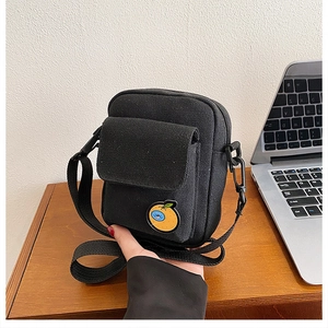 Detail of black canvas mini crossbody bag with orange fruit embroidery and adjustable strap