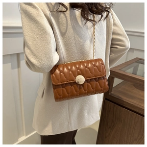 Detail van caramel crossbodytas met golfpatroon en goudkleurige kettingriem