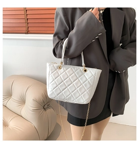 Détail du sac à main matelassé blanc avec chaîne dorée et coutures losanges