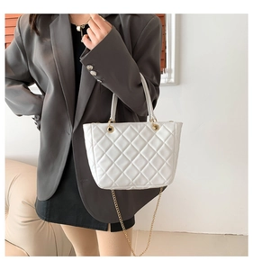 Détail d'un sac cabas blanc matelassé avec chaîne dorée et texture élégante chic