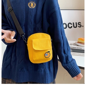 Detail of yellow canvas crossbody bag featuring a cute orange patch and adjustable strap