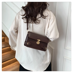 Detail of dark brown vintage faux leather shoulder bag with gold metal twist lock and straps