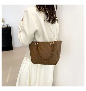 Détail d'un sac à main marron matelassé avec bandoulière en chaîne dorée et coutures