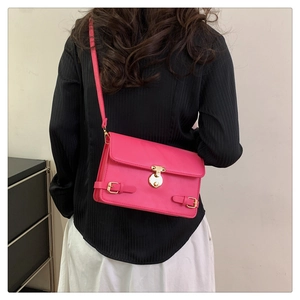 Detail view of bright pink crossbody bag with golden metal buckle and retro straps