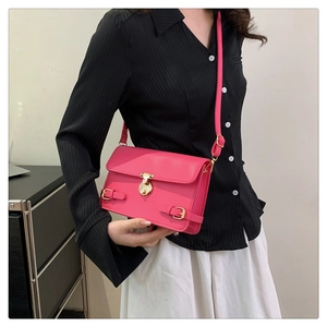On-body shot of a vibrant rose pink faux leather crossbody bag with gold buckle hardware
