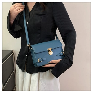 Detail view of a vintage dark blue crossbody bag with gold lock and buckle accents