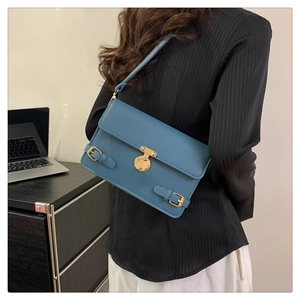 Detailed side view of grey-blue shoulder bag with gold metal buckle on a model