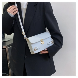 Close-up of white crossbody bag with gold hardware buckle and minimalist strap details