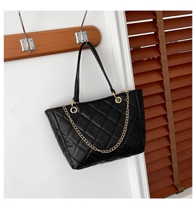 Vue détaillée du sac cabas matelassé noir avec chaîne dorée sur crochet en bois