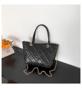 Gros plan d'un sac cabas noir matelassé avec chaîne dorée et texture en cuir PU raffiné