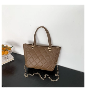 Détail du sac cabas matelassé marron avec chaîne dorée et anneaux métalliques élégants