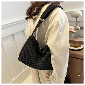 Detail einer schwarzen Hobo-Tasche mit Strass und breitem Riemen an einem Model im Café