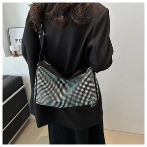 Detail der blauen Strass-Umhängetasche mit breitem Gurt, getragen von einem Modell im Raum