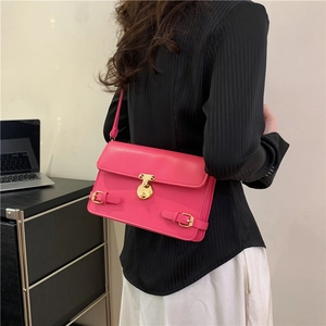 Fashionable bright pink leather shoulder bag with gold clasp shown on a female model