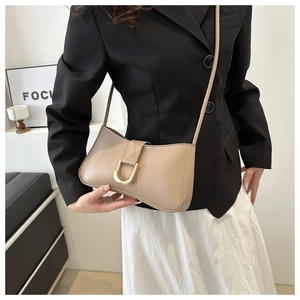 Detail of a beige leather shoulder bag with a stylish gold U-shaped metal buckle closure