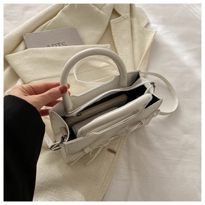 Vue ouverte du mini sac blanc avec détail nœud montrant la capacité de rangement interne