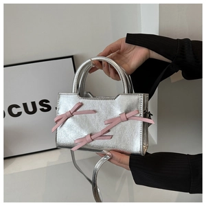 Détails du sac à main argenté métallisé avec nœuds roses et bandoulière amovible