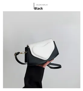 Detail of a chic black and white color-block crossbody bag with heart-shaped flap and gold hardware