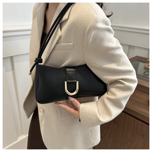 Detail of a vintage black leather underarm bag featuring a golden U-shaped metal buckle