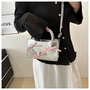 Détail du sac à main argenté métallisé avec trois nœuds en satin rose style balletcore