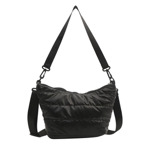 Borsa a tracolla trapuntata nera lucida con tracolla regolabile su uno sfondo bianco neutro