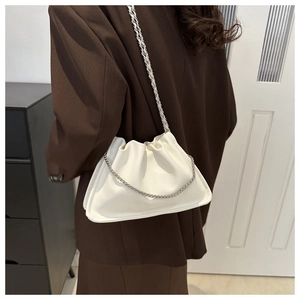 Détail du sac nuage plissé blanc avec chaîne argentée porté sur un blazer marron