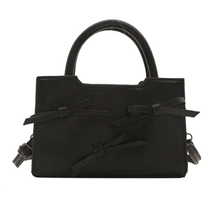 Sac à main noir doux avec nœuds en cuir et bandoulière réglable sur fond blanc pur