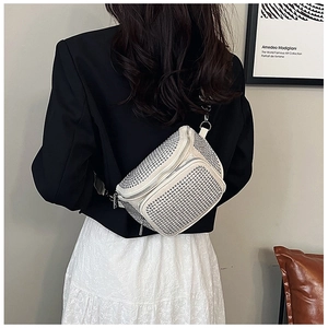 Détail d'un sac bandoulière blanc crème avec strass argentés porté par un mannequin