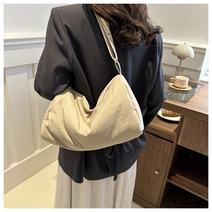 Beige nylon crossbody hobo bag with adjustable strap worn by a model in a cozy interior