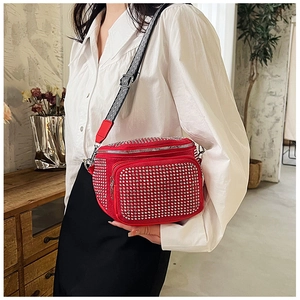 Détail du sac bandoulière rouge avec strass et sangle à chevrons noir et blanc