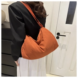 Detail of the orange half-moon crossbody bag in lightweight nylon with adjustable strap