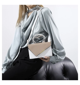 Detail einer minimalistischen Umhängetasche mit asymmetrischer Klappe und Metallgriff
