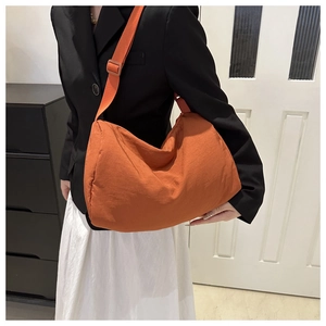 Close-up of caramel crescent crossbody bag with adjustable wide strap on model