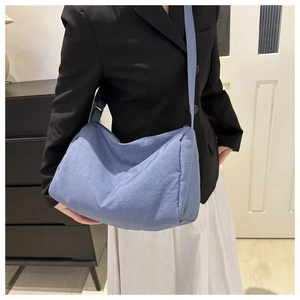 Detailed view of light blue nylon crossbody bag with adjustable strap worn by model