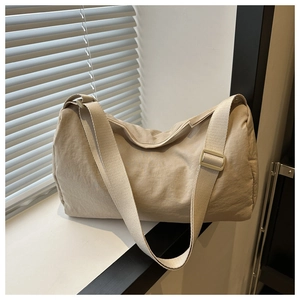 Detail of minimalist beige canvas crossbody bag showing smooth zipper and wide strap