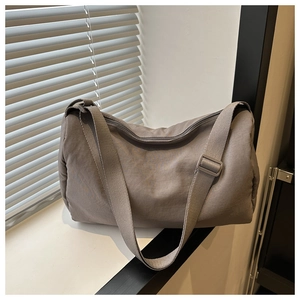Close-up of a grey canvas crossbody bag featuring a cylinder pillow shape and wide strap