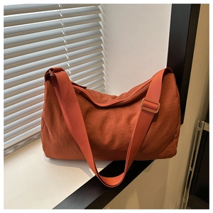 Detail of orange nylon crossbody bag featuring textured fabric and adjustable strap