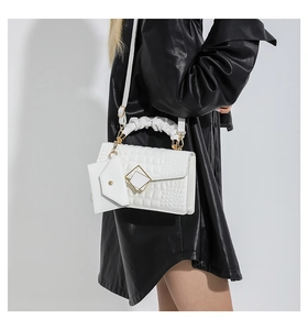 Detailed side view of white embossed crossbody bag with gold buckle and mini pouch accessory