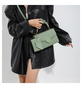 Detail of light green embossed crocodile leather handbag styled with leather jacket