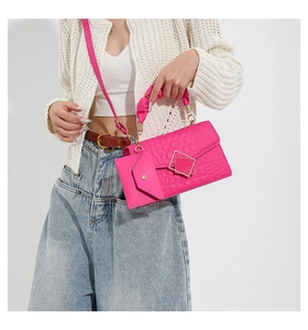 Detail of rose red embossed square handbag featuring pleated handle and mini envelope charm